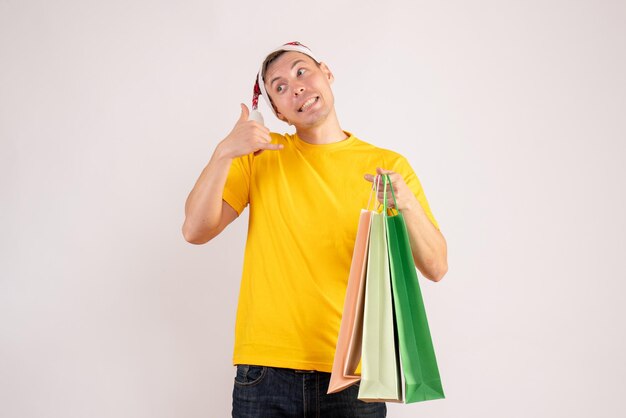 흰 벽에 쇼핑 패키지를 들고 있는 젊은 남자의 전면 모습