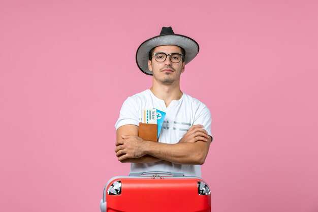 Front view of young man holding vacation tickets inside wallet on pink floor voyage man photo plane trip vacation