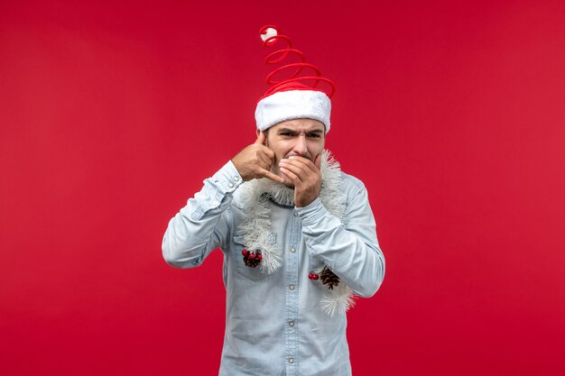 Front view of young man imitating phone call on a red wall