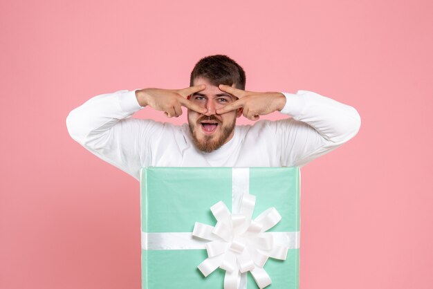 Front view of young man inside present box on the pink wall