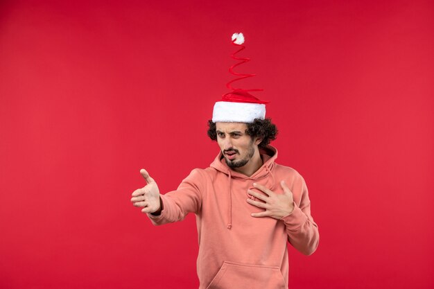 Front view of young man just standing on a red wall