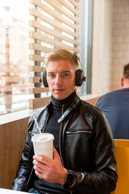Front view young man listening to music on headphones inside