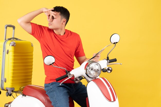 Front view young man on moped holding his nose