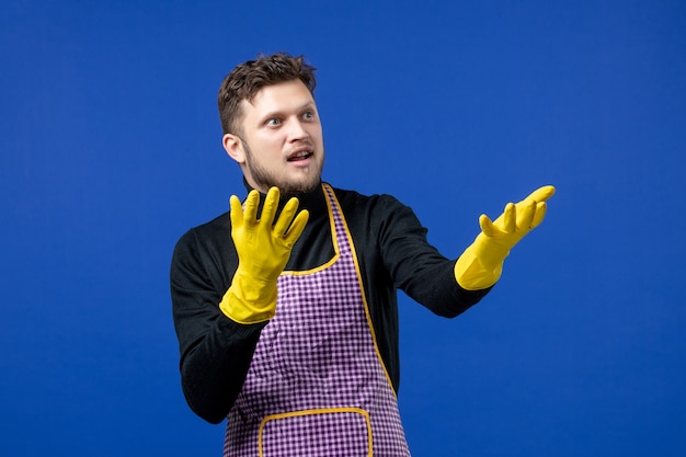 Front view of young man opening hands standing on blue wall