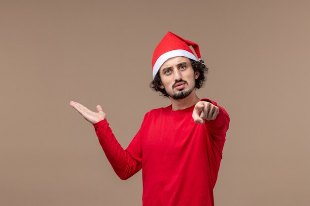 Front view young man pointing on brown background holiday emotions christmas