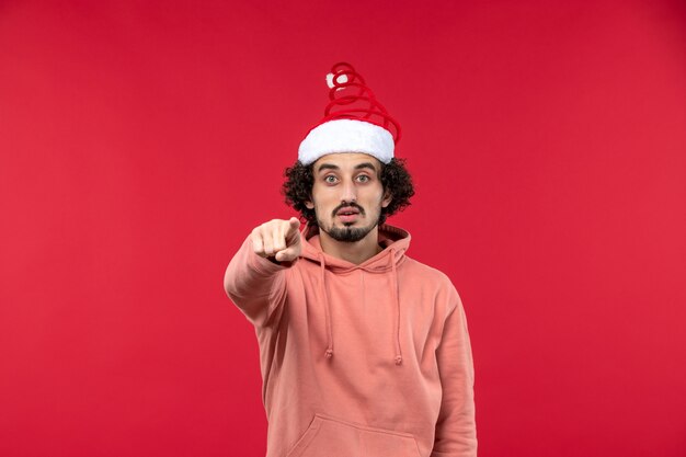 Front view of young man pointing on red wall