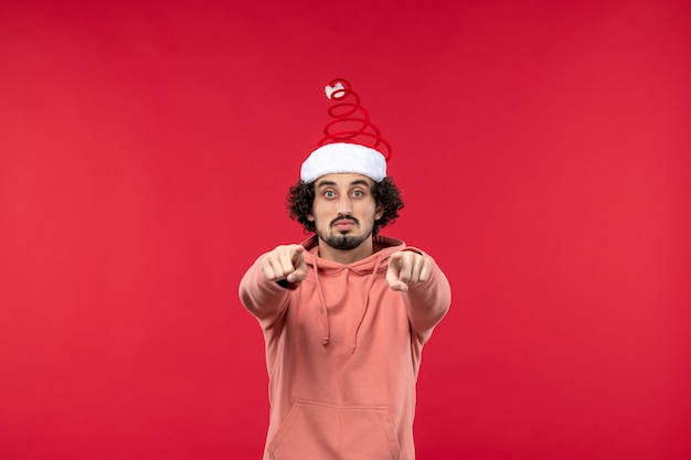 Front view of young man pointing on red wall