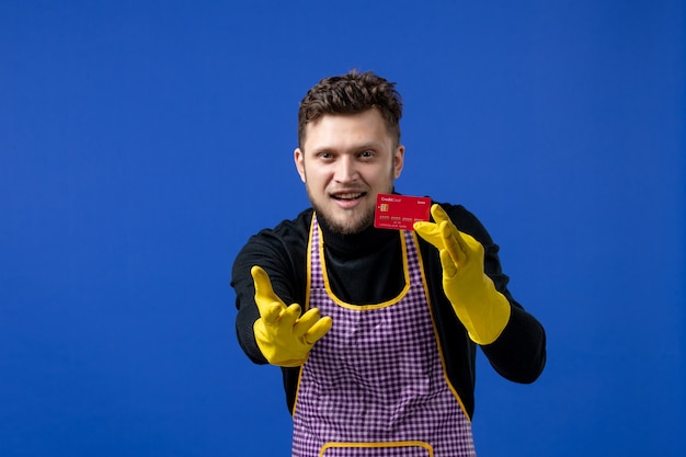 Vista frontale del giovane che allunga la mano con la carta sulla parete blu