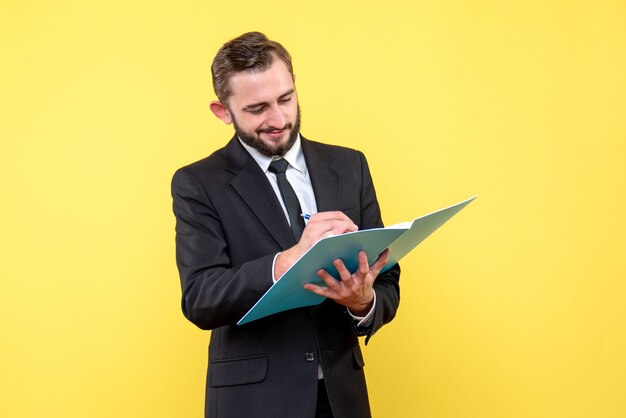 Вид спереди молодого человека доволен бизнесменом, проверяющим документы в синей папке на желтом
