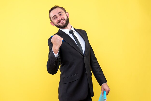 Front view of young man satisfied businessman happily holding the pen on yellow