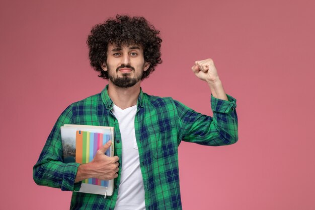 Front view young man showing his strength with notebooks