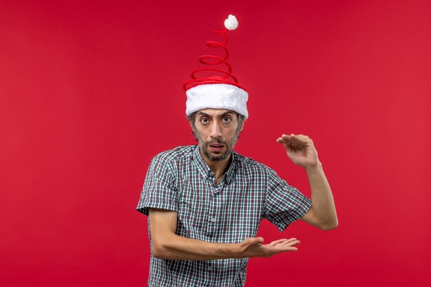 Front view of young man showing size on red wall