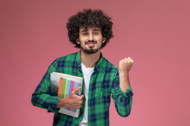 Free photo front view young man squeezing his hand with notebooks