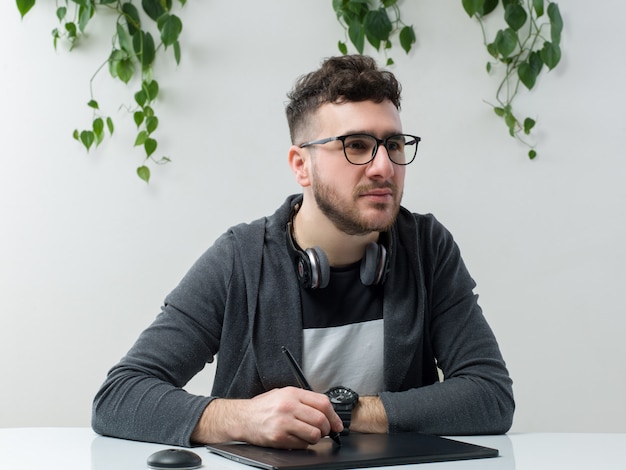 A front view young man in sunglasses sitting along with laptop on the white space