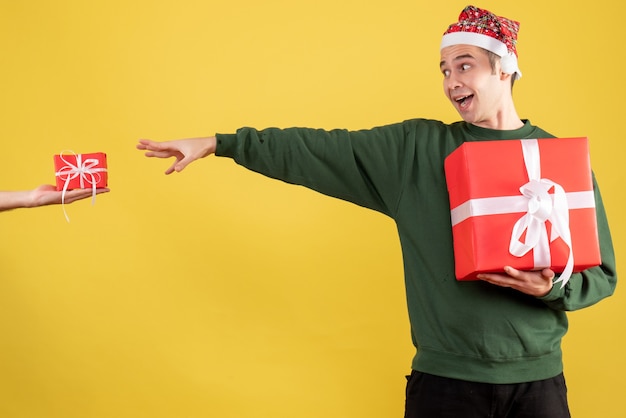 Front view young man trying to catch the gift in female hand standing on yellow 