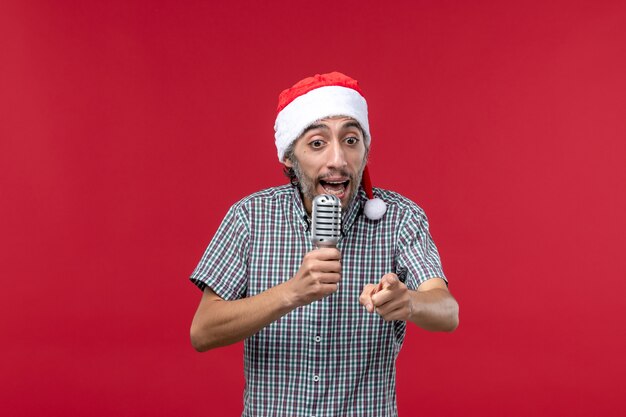 Front view young man using microphone on red wall emotion holiday singer music