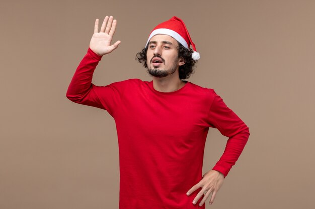 Front view young man waving on brown background holiday emotion christmas