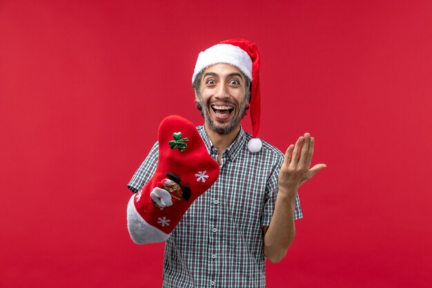 赤い壁にクリスマスの靴下を履いて若い男の正面図