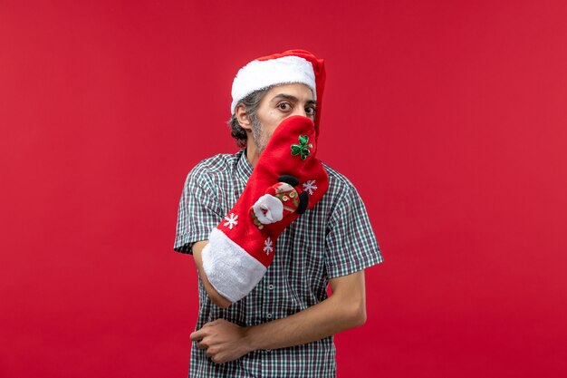 Вид спереди молодого человека в рождественском носке на красной стене