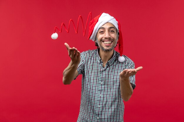 Front view of young man wearing christmas toy cap on the red wall