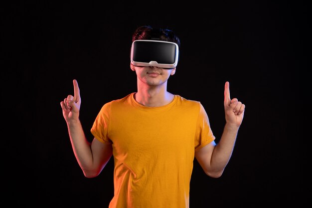 Front view of young man wearing virtual reality headset on dark wall