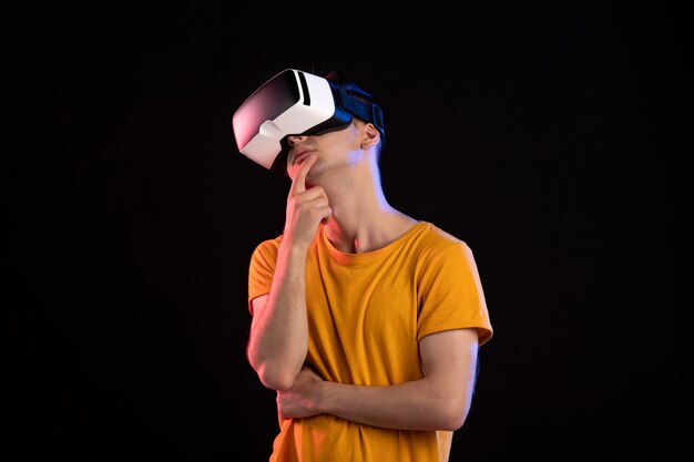 Front view of young man wearing virtual reality headset on dark wall