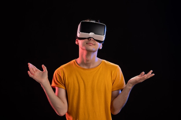 Front view of young man wearing vr headset on dark wall