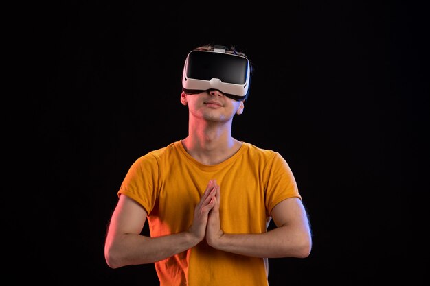 Front view of young man wearing vr headset on dark wall