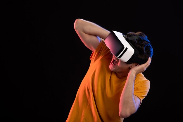 Front view of young man wearing vr headset on dark wall