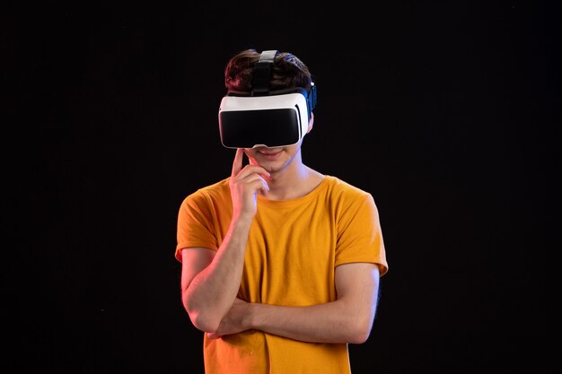 Front view of young man wearing vr headset on the dark wall