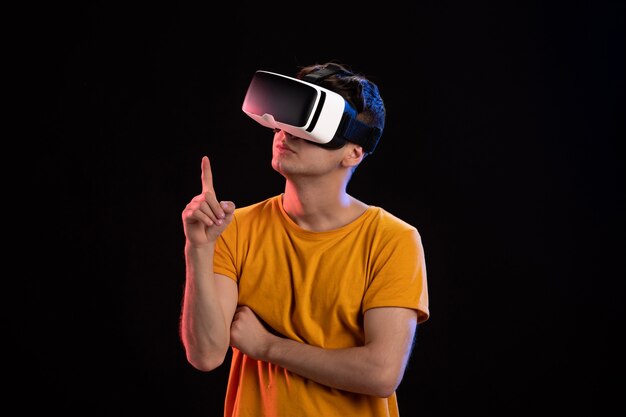 Front view of young man wearing vr headset on the dark wall