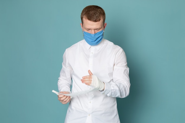 Free photo a front view young man in white shirt and blue gloves on the blue space