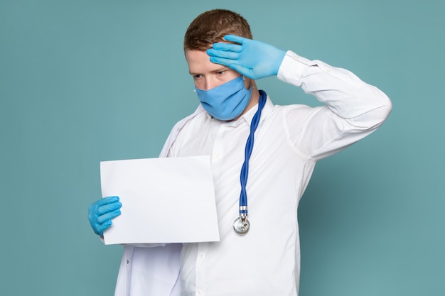 Free photo a front view young man in white shirt and blue gloves with blue mask on the blue space