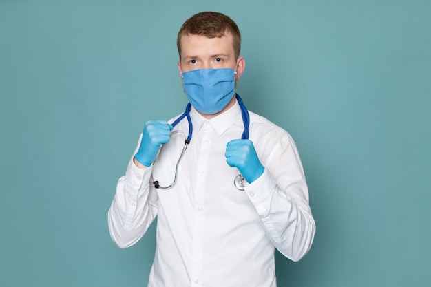 A front view young man in white shirt and blue gloves with blue mask on the blue space