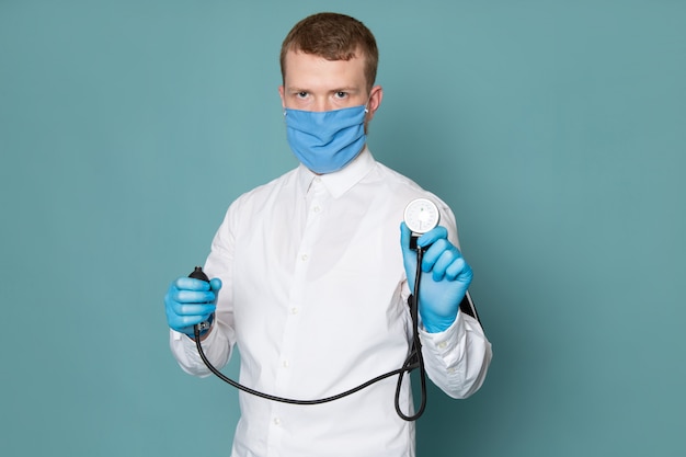 A front view young man in white shirt and blue gloves with mask on the blue space