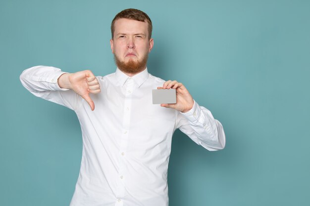 A front view young man in white shirt holding card on the blue space