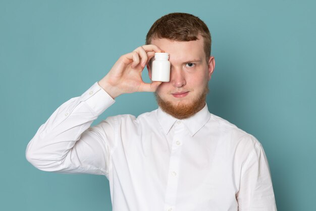 A front view young man in white shirt holding little can on the blue space