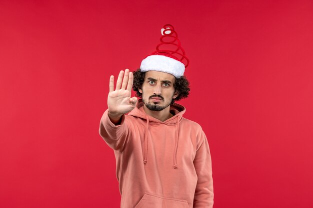 Front view of young man with angry expression on red wall