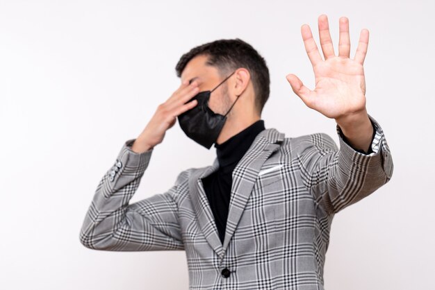 Front view young man with black mask covering his eyes standing on white isolated background