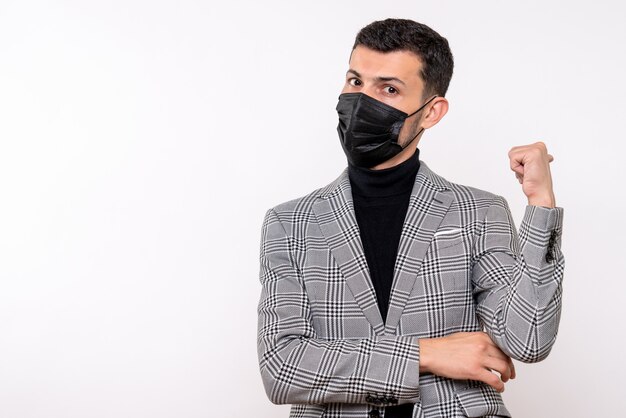 Front view young man with black mask pointing at back standing on white isolated background