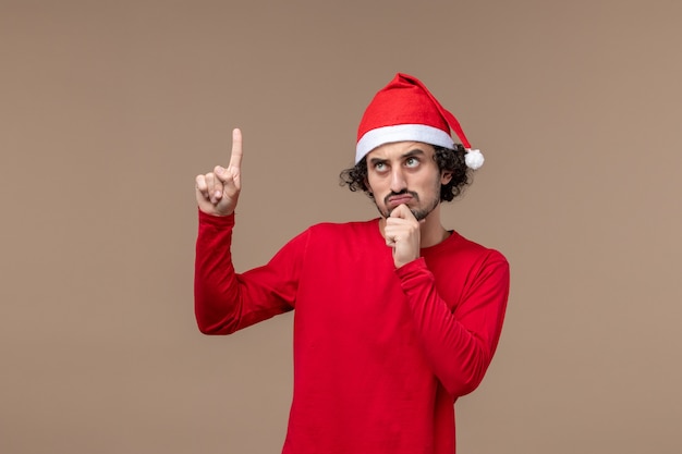 Free photo front view young man with christmas cape on brown desk emotion holiday christmas