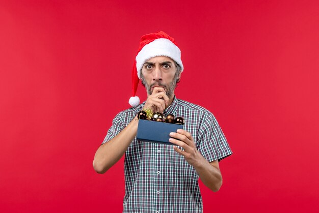 Front view young man with christmas tree toys on red desk