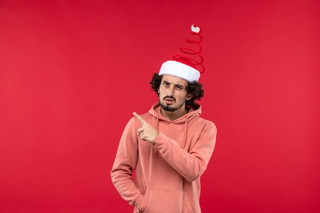 Front view of young man with confused expression on a red wall