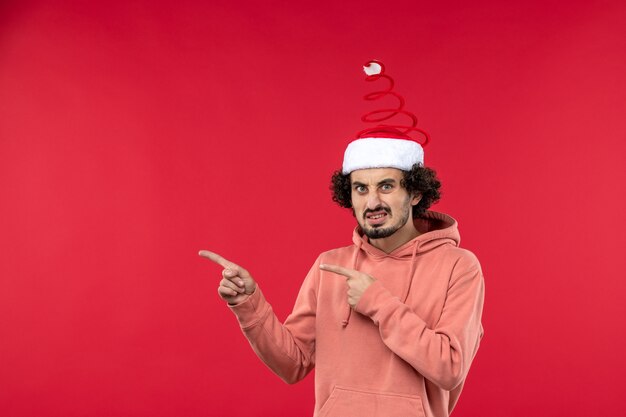 Front view of young man with confused expression on red wall