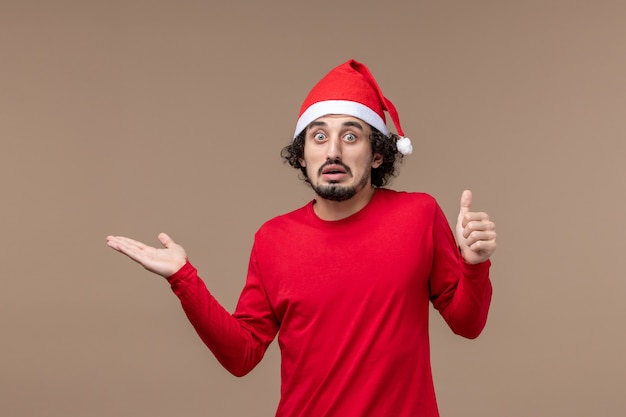 茶色の背景の休日の感情のクリスマスに混乱した顔を持つ正面図若い男