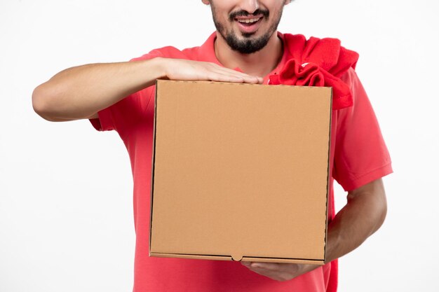 Вид спереди молодого человека с коробкой для доставки еды на белой стене