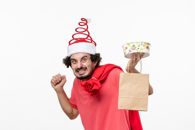 Front view of young man with delivery food on a white wall