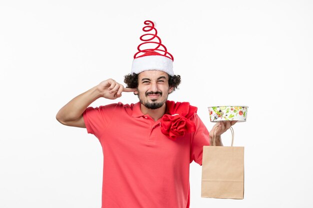 Front view of young man with delivery food on white wall