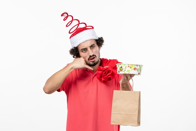 Front view of young man with delivery food on white wall