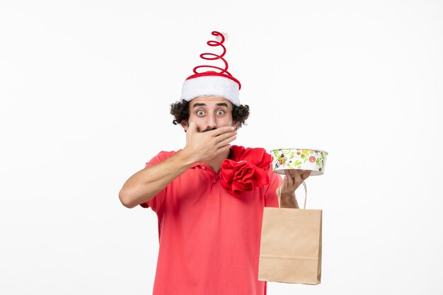 Front view of young man with delivery food on white wall